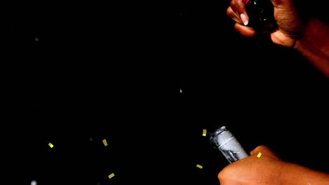 Animation-of-confetti-over-man-opening-champagne-on-black-background