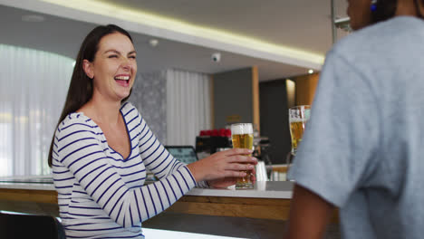 Diverse-group-of-happy-friends-drinking-beers-and-talking-at-a-bar