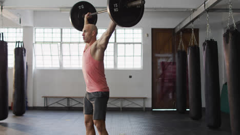 Caucasian-male-trainer-working-out-with-barbell-at-the-gym