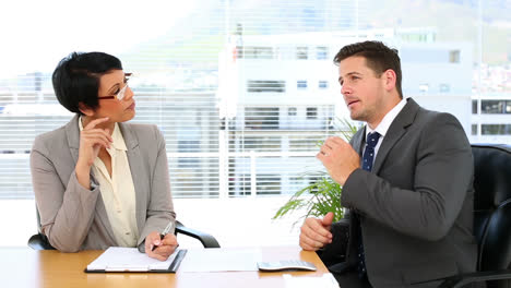 Handsome-businessman-talking-with-his-colleague-at-desk