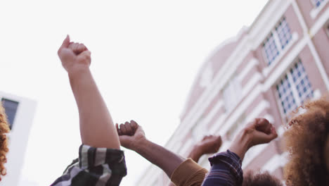 Diverse-group-of-men-and-women-shouting-raising-fists-during-protest