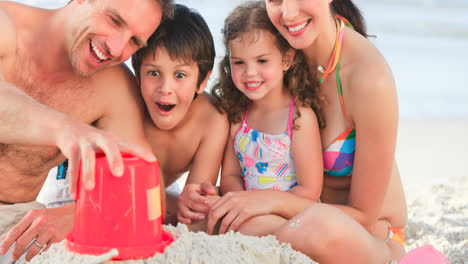 Porträt-Einer-Lächelnden-Kaukasischen-Familie-Im-Urlaub,-Die-Am-Meer-Mit-Sand-Spielt