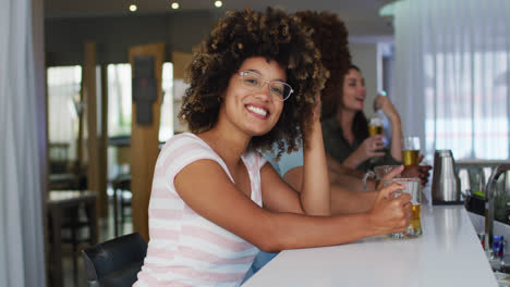 Diverse-group-of-happy-friends-drinking-beers-and-smiling-at-a-bar