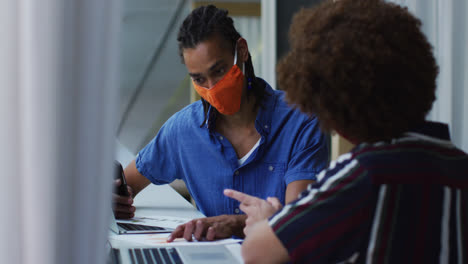 Diverse-business-colleagues-wearing-face-masks-in-discussion-at-a-casual-meeting