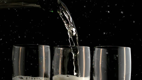 Animation-of-snow-falling-over-champagne-glasses-on-black-background