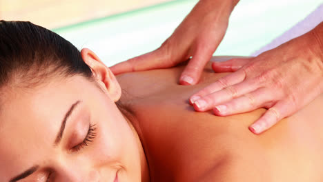 Happy-brunette-enjoying-a-massage-poolside