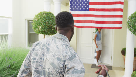 African-american-male-soldier-embracing-his-smiling-wife-over-american-flag