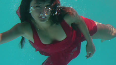 Brunette-in-evening-gown-swimming-in-pool-and-waving