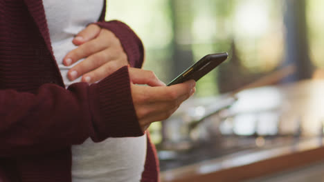 Manos-De-Una-Mujer-Embarazada-Caucásica-Tocando-El-Vientre-Y-Usando-Un-Teléfono-Inteligente