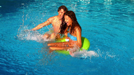 Pareja-Joven-Chapoteando-Y-Divirtiéndose-En-La-Piscina