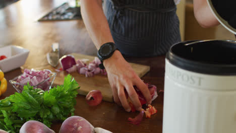 Hands-of-caucasian-pregnant-woman-wearing-apron,-putting-peels-into-trash-bin