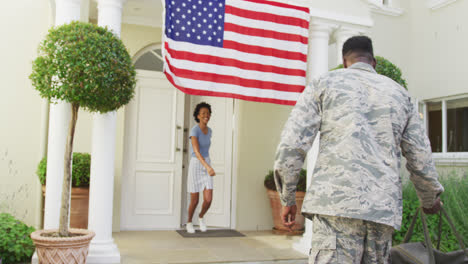 African-american-male-soldier-embracing-his-smiling-wife-over-american-flag