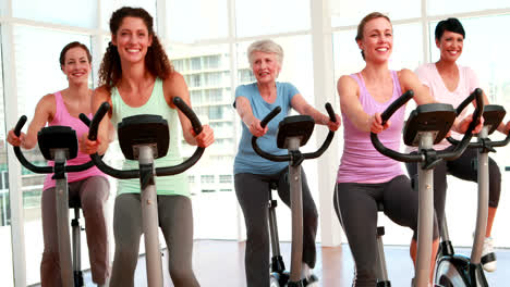 Grupo-De-Mujeres-Sonrientes-Haciendo-Una-Clase-De-Spinning