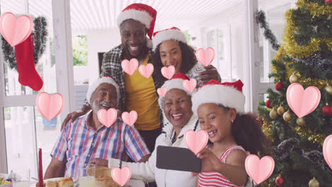 Animación-De-Iconos-De-Corazón-Sobre-Familia-Afroamericana-Con-Gorros-De-Papá-Noel.