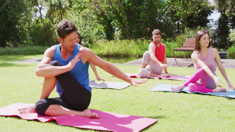 Eine-Vielfältige-Gruppe-Von-Männern-Und-Frauen-Praktiziert-Yoga-Auf-Matten-Im-Sonnigen-Park