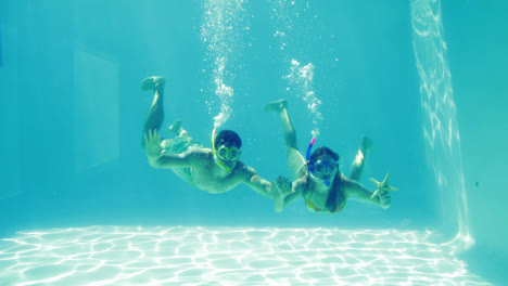 Pareja-Feliz-Saltando-A-La-Piscina-Usando-Snorkels-Y-Sosteniendo-Estrellas-De-Mar