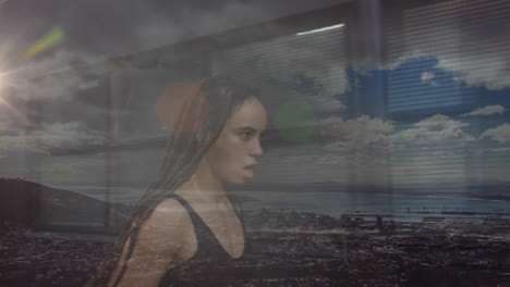 Composite-of-mixed-race-woman-with-dreadlocks-running,-and-coastal-landscape-with-cloudy-blue-sky