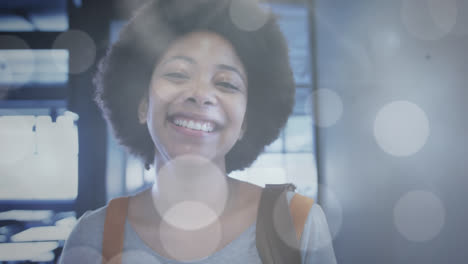 Animation-of-light-spots-over-smiling-african-american-businesswoman