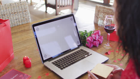 Mujer-Birracial-Feliz-Con-Regalos-Haciendo-Videollamadas-Con-Laptop-Para-El-Día-De-San-Valentín,-Con-Espacio-Para-Copiar-En-La-Pantalla