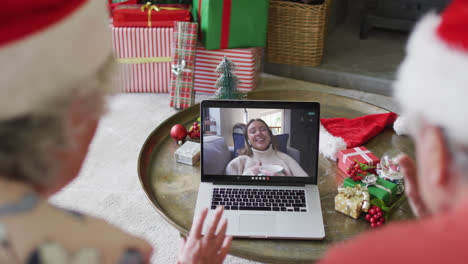 Pareja-Caucásica-Mayor-Usando-Una-Computadora-Portátil-Para-Una-Videollamada-Navideña-Con-Una-Mujer-Feliz-En-La-Pantalla