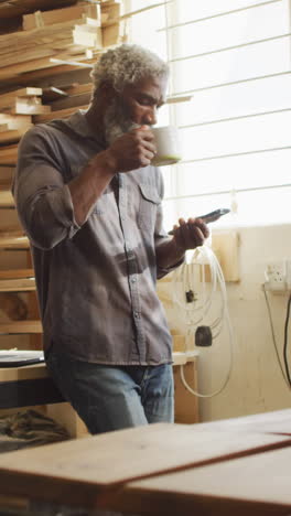 African-American-man-sips-coffee-in-a-workshop,-with-copy-space