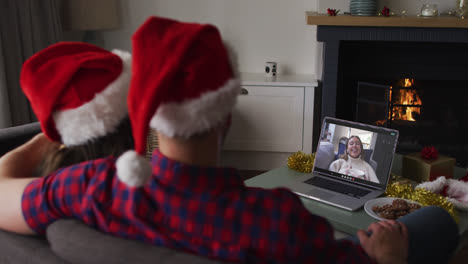 Caucasian-couple-on-laptop-video-call-with-female-friend-at-christmas-time