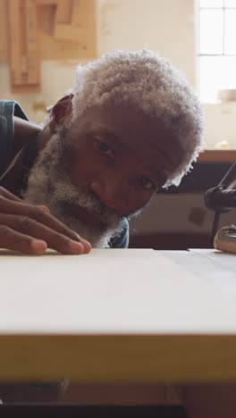 African-American-man-examines-a-piece-of-wood-in-a-workshop