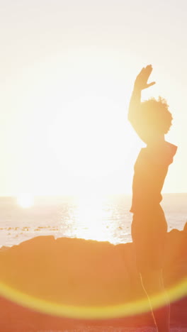 Young-biracial-woman-enjoys-a-sunset-on-the-beach,-with-copy-space