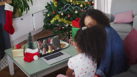 African-american-mother-and-daughter-having-a-videocall-on-laptop-at-home-during-christmas