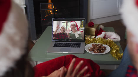 Rückansicht-Eines-Kaukasischen-Paares-Mit-Weihnachtsmützen,-Das-Während-Der-Weihnachtszeit-Einen-Videoanruf-Auf-Dem-Laptop-Führt