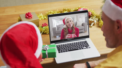 Kaukasischer-Vater-Und-Sohn-Mit-Weihnachtsmützen-Mit-Laptop-Für-Weihnachtsvideoanruf-Mit-Frau-Auf-Dem-Bildschirm