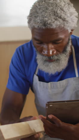 Focused-African-American-craftsman-examines-a-piece-of-wood-in-a-workshop