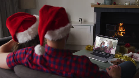 Pareja-Caucásica-En-Videollamada-Portátil-Con-Familia-Con-Máscaras-Faciales-En-Navidad