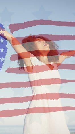 Animation-of-american-flag-over-african-american-woman-raising-hands-at-beach