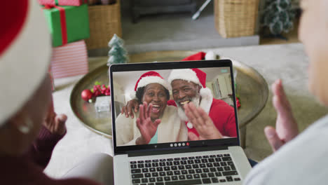 Verschiedene-ältere-Freundinnen-Nutzen-Laptop-Für-Weihnachtsvideoanruf-Mit-Glücklichem-Paar-Auf-Dem-Bildschirm