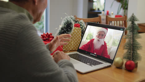 Un-Hombre-Mayor-Caucásico-Teniendo-Una-Videollamada-Navideña-En-Una-Computadora-Portátil-Con-Un-Papá-Noel-Caucásico-En-La-Pantalla