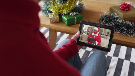 Hombre-Albino-Saludando-Y-Usando-Una-Tableta-Para-Una-Videollamada-Navideña-Con-Santa-En-La-Pantalla