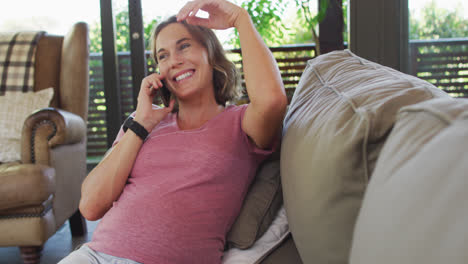 Happy-caucasian-pregnant-woman-sitting-on-sofa-and-having-phone-call