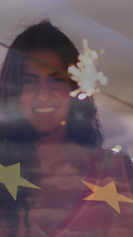 Animation-of-flag-of-european-union-over-happy-biracial-woman-with-sparklers-on-beach