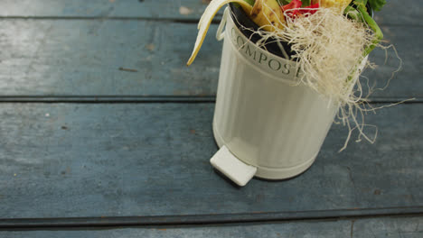 Video-of-white-compost-bin-with-organic-waste-and-copy-space-on-grey-wooden-background