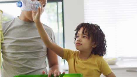 A-young-boy-gives-his-father-a-high-five-in-the-kitchen,-with-copy-space