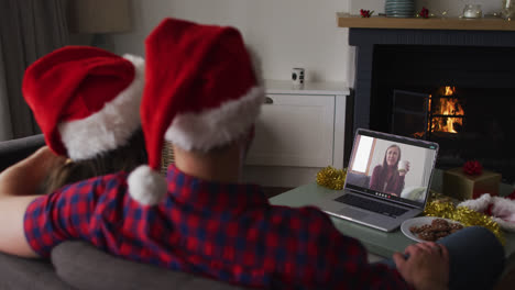 Rückansicht-Eines-Kaukasischen-Paares-Mit-Weihnachtsmützen,-Das-Während-Der-Weihnachtszeit-Einen-Videoanruf-Auf-Dem-Laptop-Führt