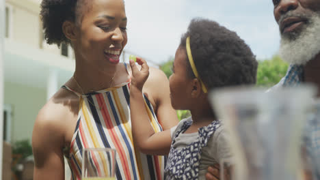 Happy-african-american-family-feeding-and-having-breakfast-in-garden