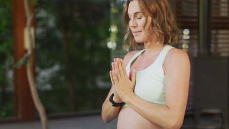 Relaxed-caucasian-pregnant-woman-practicing-yoga-in-terrace