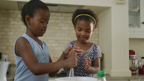 Glückliche-Zwei-Afroamerikanische-Mädchen-Backen-Und-Mischen-Zutaten-In-Der-Küche