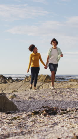 Biracial-couple-enjoys-a-beach-walk,-with-copy-space