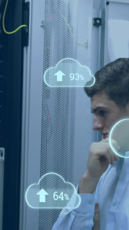 Animation-of-clouds-with-increasing-numbers-over-smiling-caucasian-man-standing-at-servers