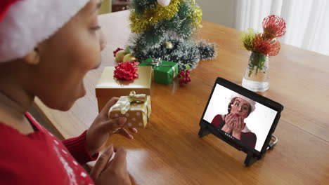 Mujer-Afroamericana-Con-Sombrero-De-Santa-Usando-Tableta-Para-Videollamada-Navideña-Con-Mujer-En-Pantalla