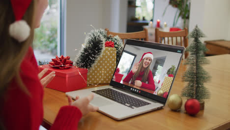 Caucasian-woman-on-laptop-video-call-with-happy-female-friend-at-christmas-time