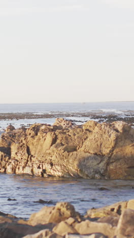 Rocky-shoreline-bathed-in-soft-light,-with-copy-space